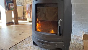 A wood-burning stove with a glass door, a wooden cabinet, and a patterned floor. - Relaxing peaceful retreat for 2 in a rural village in the Pyrenees (Rabouillet)