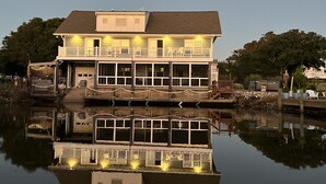 A multi-story waterfront house with a balcony and a dock extending into the water. - Beautiful home in quiet beach neighborhood on canal. Five minute walk to beach. (Virginia Beach)