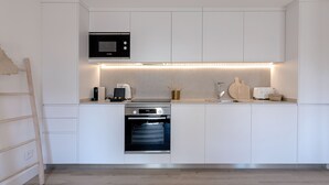 Eine moderne Küche mit weißen Schränken, einer eingebauten Mikrowelle, einer Kaffeemaschine, einem Toaster und einem Backofen.