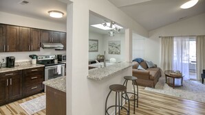 A modern kitchen with dark wooden cabinets, a granite countertop, and a central island with stools. - Family friendly home near Colonial Williamsburg and Busch  Gardens (Williamsburg)