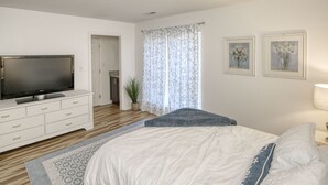 A bedroom with a bed, a TV on a white dresser, a plant, and two framed pictures on the wall. - Family friendly home near Colonial Williamsburg and Busch  Gardens (Williamsburg)