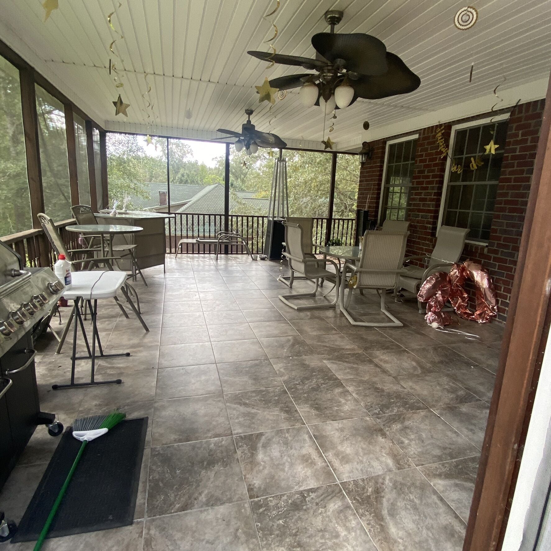 A covered patio area with a grill, seating, and a ceiling fan.