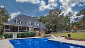Piscina residencial com uma casa ao fundo.