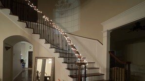 Uma imponente escadaria com design curvo, corrimãos de madeira e luzes decorativas.