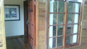 A wooden interior with a large sliding glass door leading to a deck. - Casa del campo (Tela)