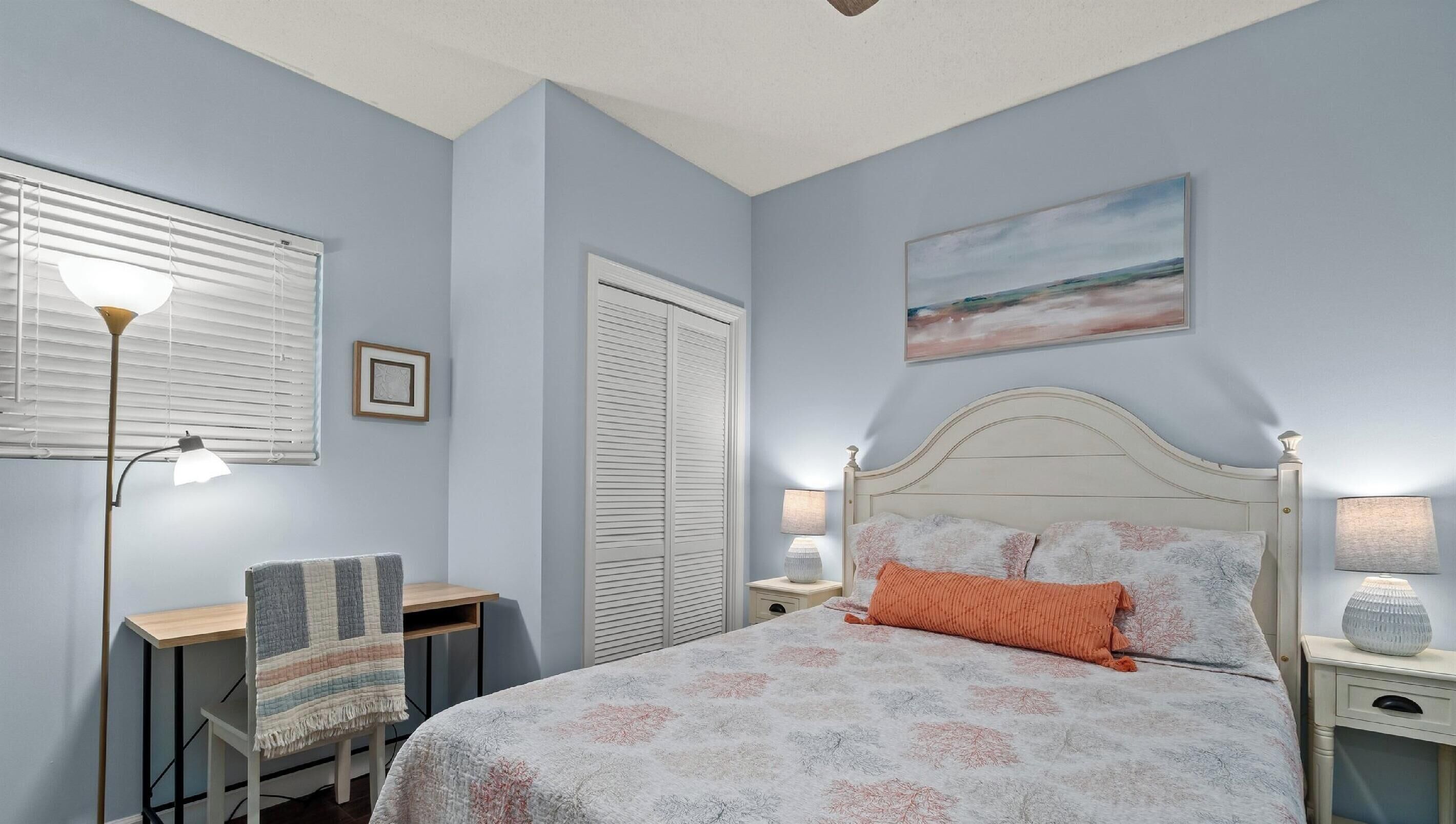 A bedroom with a bed, bedside tables, a desk, and a chair.
