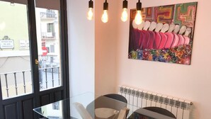 A modern room with a glass table, two chairs, a radiator, and a colorful painting on the wall. - Navarro Suite Pamplona - Family Management (Pamplona)
