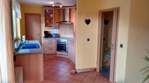 Une cuisine de taille réduite, dotée de meubles de rangement en bois, d’un four encastré et d’un évier.