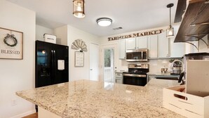 A kitchen with granite countertops, stainless steel appliances, and a 'Farmers Market' sign. - Hot tub, sep. game room, wrap porch,quiet street,fire-pit,2 acres. All ages! (Wimberley)