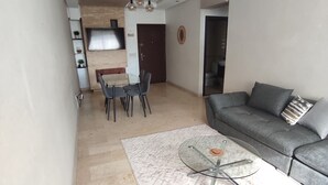 Una sala de estar moderna con un sofá gris, una mesa de centro de vidrio y una araña.