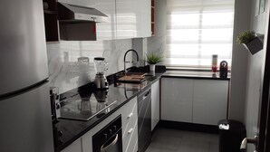 Una cocina moderna con armarios blancos, encimera negra y horno empotrado.