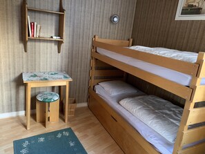 A bunk bed with a small table and chair, a shelf with books, and a wall-mounted light. - Superb apartment with uninterrupted mountain views (Huez)