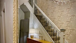 A staircase with a white railing, a wooden cabinet, and a door with a decorative frame.