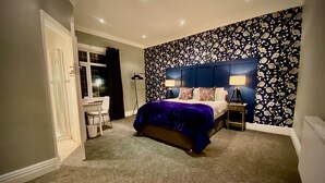 A bedroom with a bed, bedside tables, a desk, and a chair.