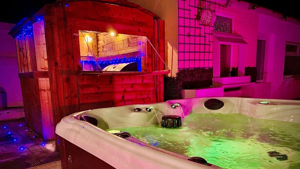 A hot tub with a wooden structure and a clock on the wall.