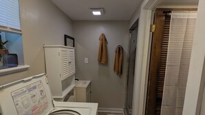 Un cuarto de lavandería con lavadora y secadora de carga frontal, un lavamanos pequeño y un tendedero.