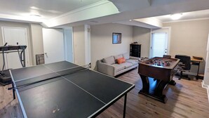 Una sala de estar con mesa de ping pong, mesa de fútbolín, sofá y una mesa de centro.