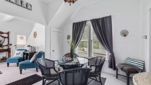 A modern living room with a round glass table, black mesh chairs, a blue sofa, and a small round table with a striped cushion. - Charming, cozy, vintage house located in the historic Silver Valley. (Mullan)