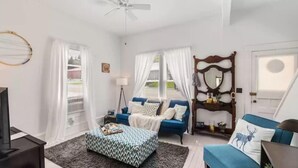A well-lit room with a bed, a sofa, a television, and a ceiling fan. - Charming, cozy, vintage house located in the historic Silver Valley. (Mullan)