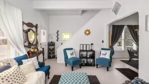A spacious living room with a high ceiling, a staircase, and a view of the outdoors. - Charming, cozy, vintage house located in the historic Silver Valley. (Mullan)