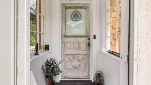 A white door with a 'Welcome' sign above it, flanked by windows on either side. - Charming, cozy, vintage house located in the historic Silver Valley. (Mullan)