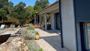 Et moderne hus med en overdækket terrasse, swimmingpool og en anlagt have.