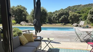 Et udendørs opholdsområde med pool, sofa og bord.