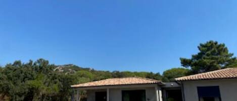Uma área junto à piscina com espreguiçadeiras e um pequeno edifício com telhado em azulejos.