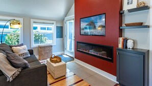 A modern living room with a fireplace, a sofa, a coffee table, and a red accent wall. - Courtside Cottage - WalkScore 93 - Dog Friendly (Ashland)
