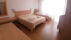 Una habitación de hotel con dos camas, un escritorio, una silla, un espejo y una ventana con cortinas.