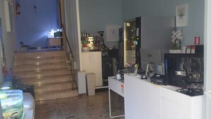 Una cocina con encimera blanca, estufa y refrigerador. Una escalera conduce a otra habitación.