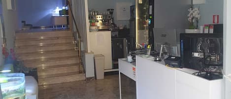 A kitchen with a white countertop, a stove, and a refrigerator. There is a staircase leading to another room.