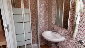 Un baño con ducha, lavabo y espejo.