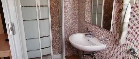 A bathroom with a shower, a sink, and a mirror.