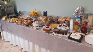 Una mesa de buffet con diversas opciones de comida, como frutas, pasteles y postres.