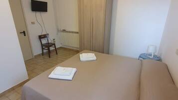 Une chambre d’hôtel équipée d’un lit, d’une chaise, d’un téléviseur, d’un climatiseur et d’une porte.