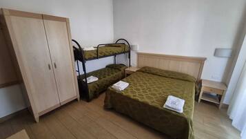Ein Zimmer mit Etagenbetten, einem Kleiderschrank, einem Nachttisch und einer Lampe.