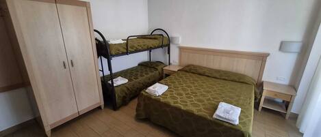 A room with bunk beds, a wardrobe, a bedside table, and a lamp.