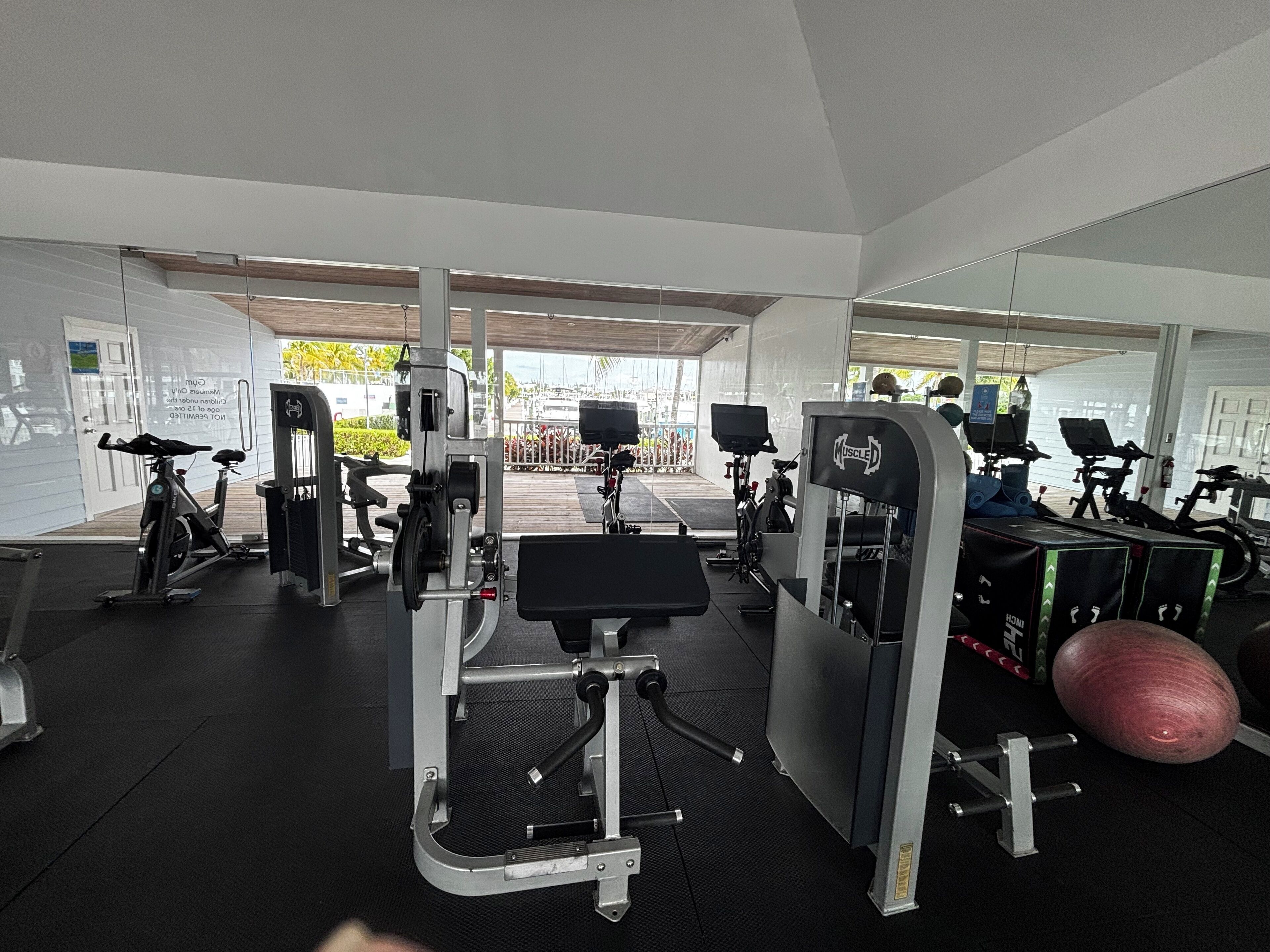 Une salle de sport équipée de divers appareils d’exercice, notamment des tapis de course, des vélos d’appartement et des appareils de musculation.