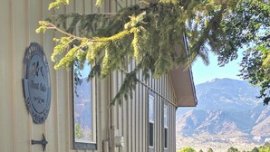 A building with a stone facade, a welcome sign, and a view of mountains. - Grandview Mesa - Amazing Mountain Views!!! (Colorado Springs)
