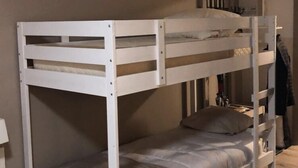 A bunk bed in a room with a wooden floor and a plain wall. - Lodging in the woods (Les Deserts)