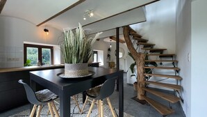 Una cocina moderna con encimera oscura, una mesa de comedor con sillas y una escalera con escalones de madera.