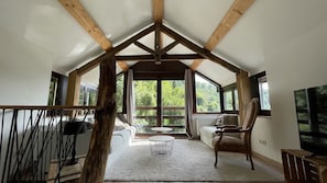 Um amplo quarto estilo loft com teto alto, janelas grandes, área de estar aconchegante e televisão.