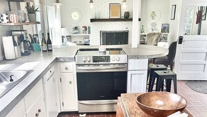 A kitchen with a brick floor, white cabinets, a wooden table, and a large bowl.