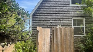 A wooden house with a shingled exterior, a window, and a wooden gate.