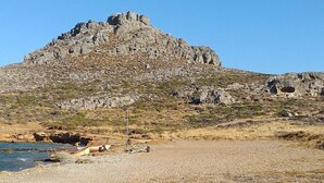 Une plage de galets avec une grande colline en arrière-plan.