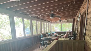 Un espace extérieur abrité, doté d’un plancher en bois, d’une rambarde et offrant une vue sur l’extérieur.