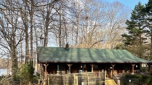 Un chalet rustique avec un toit végétalisé, une véranda en bois et une entrée clôturée.