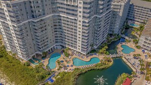 Un hotel moderno con múltiples balcones, un área de piscina central y ubicación frente a la playa.