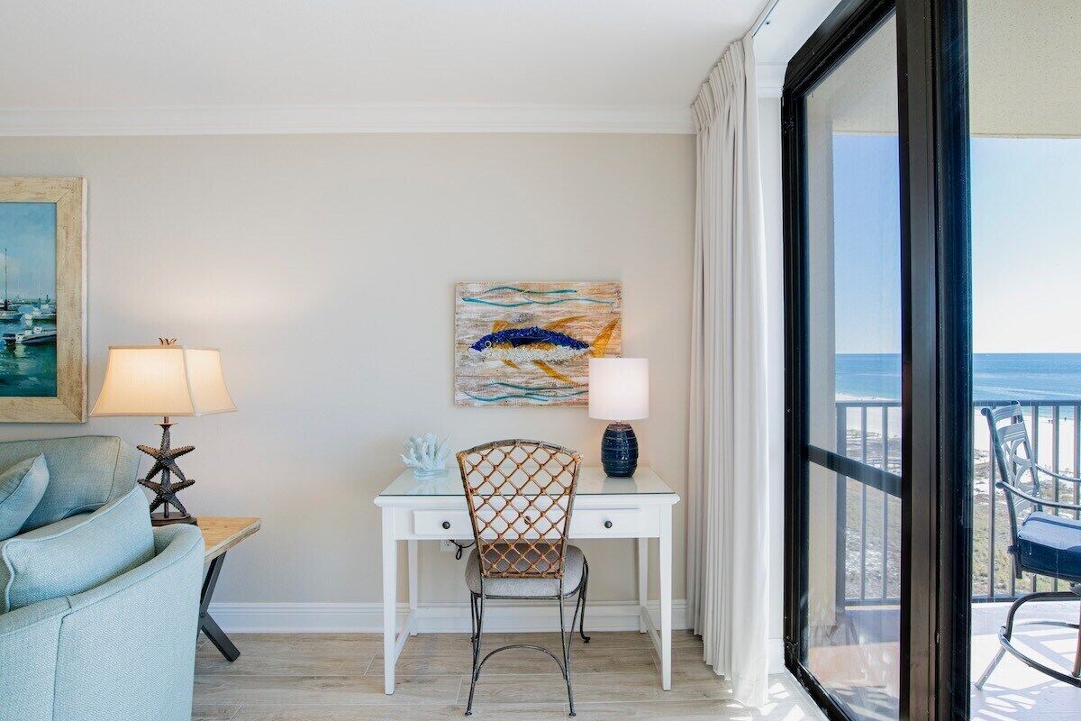 A room with a desk, chair, and a view of the ocean.